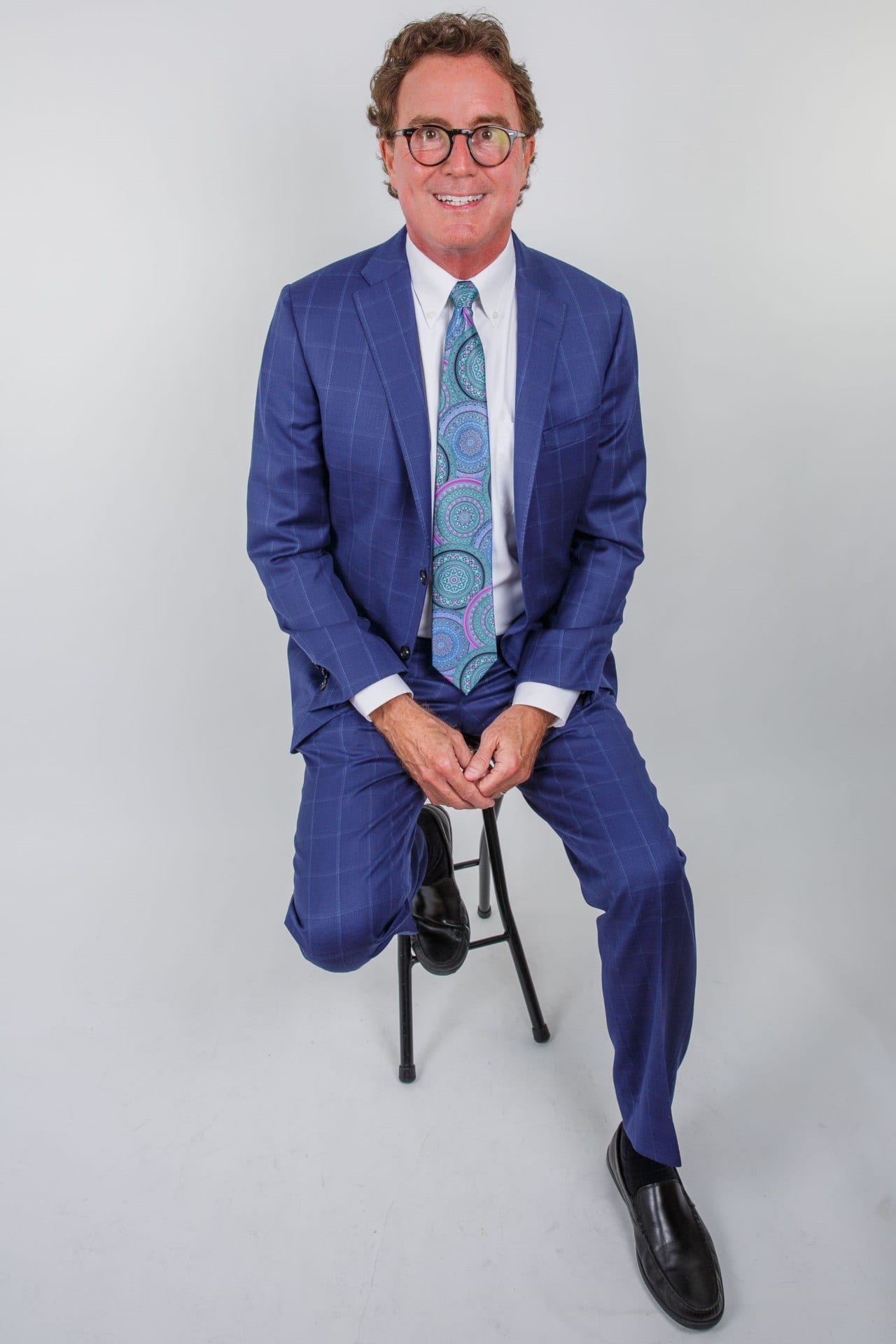 Michael Bird in Blue Suit, sitting on a stool